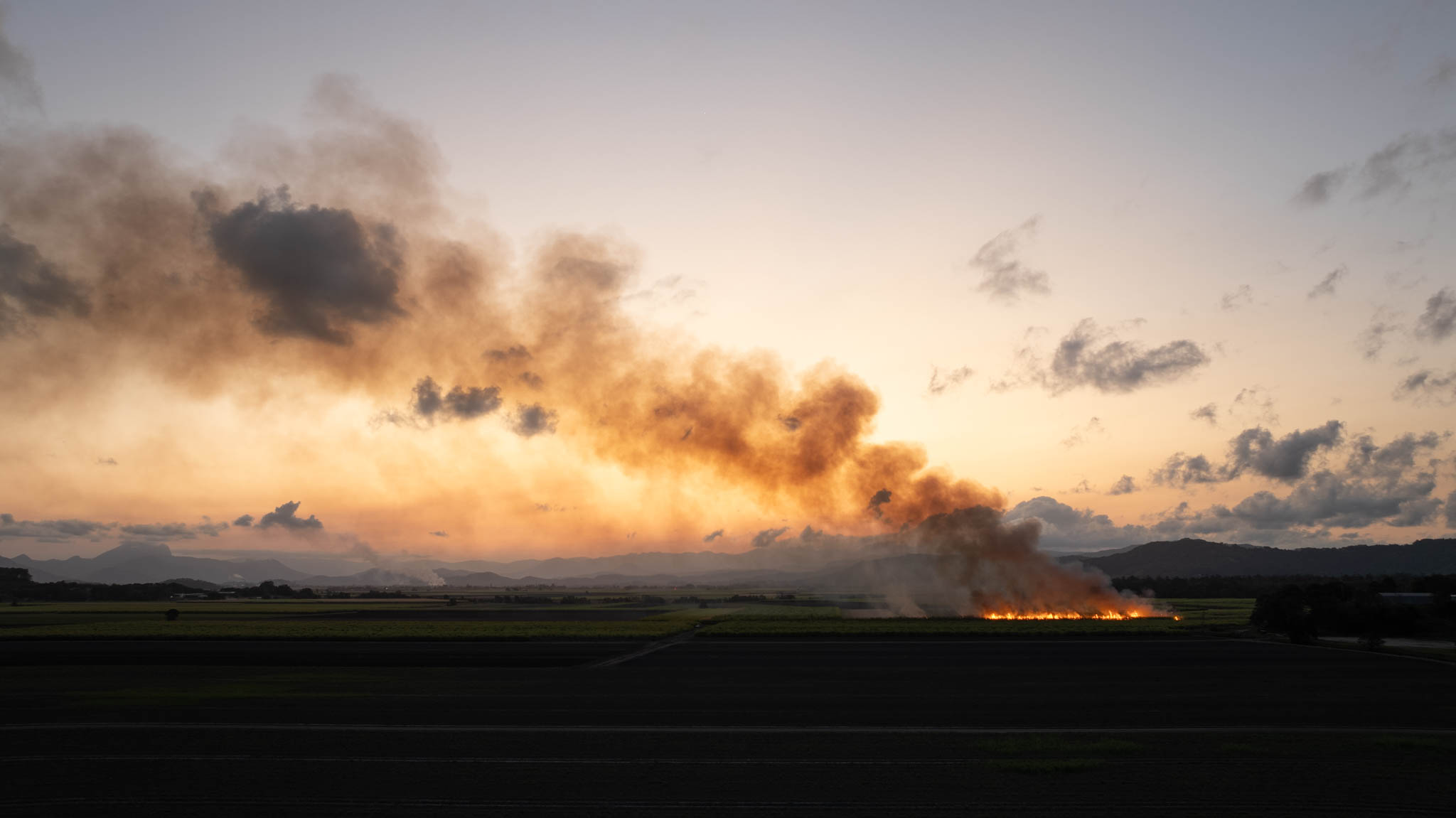 Cane fires lit at dusk along the Tweed