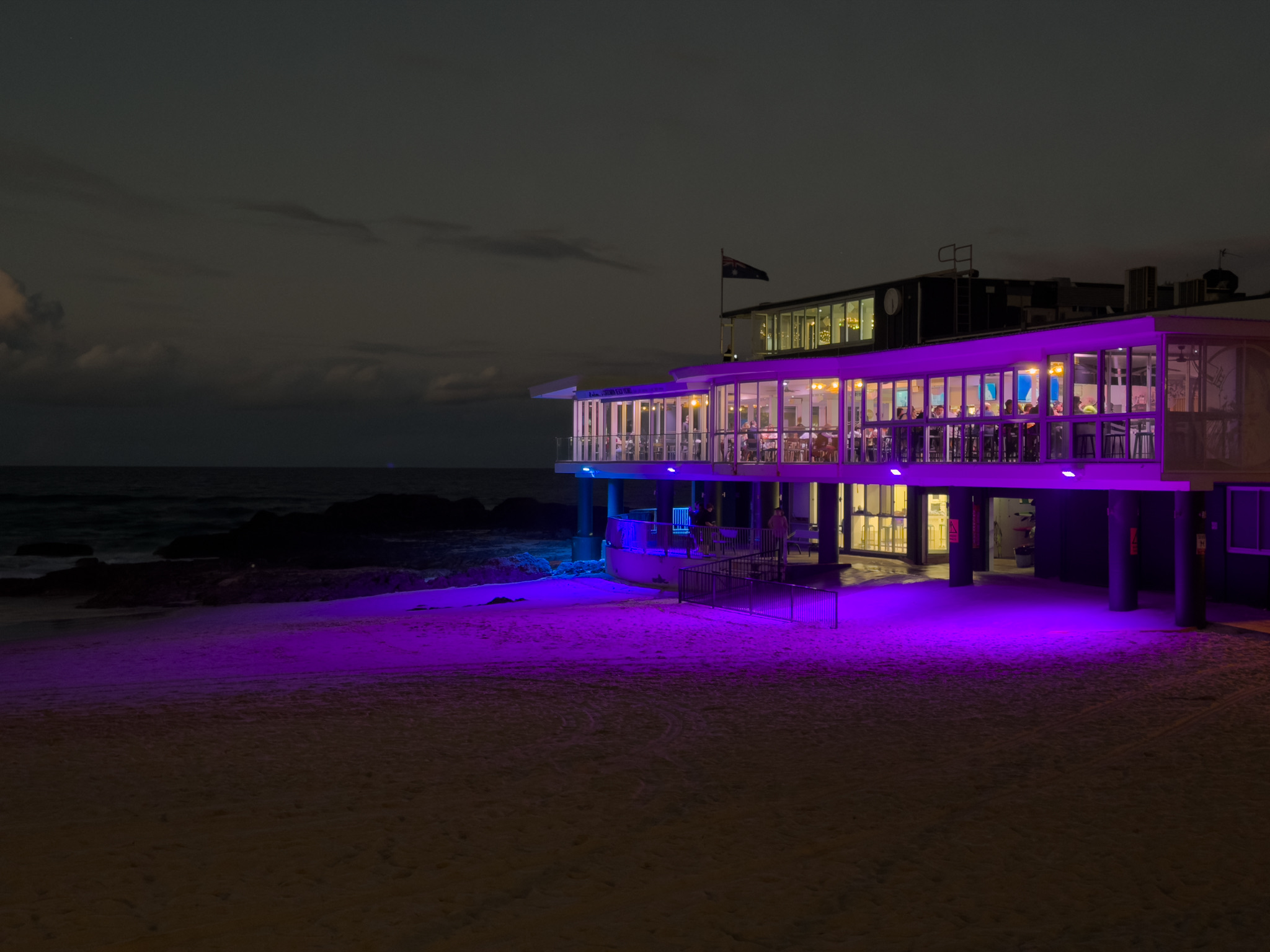 The Currumbin surf life saving club lit up on the beach at dusk.