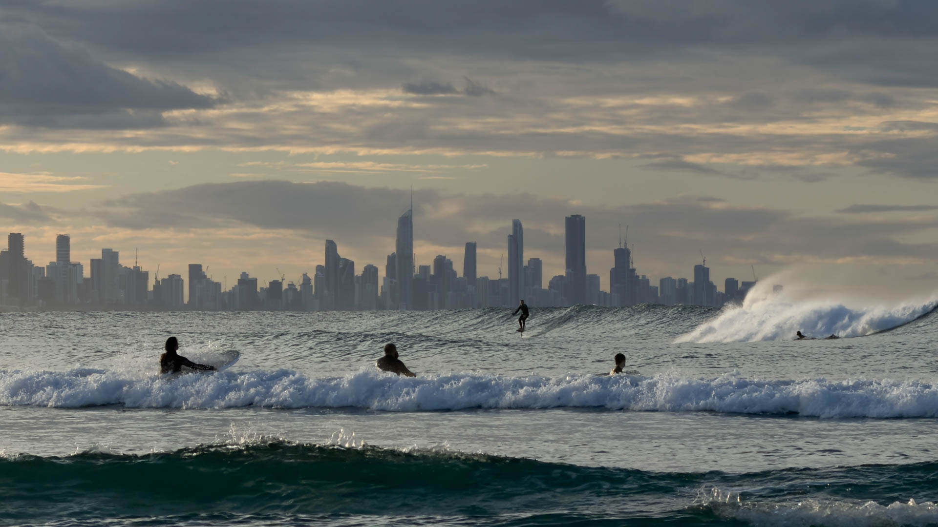 Surfers in the line-up off Currumbin Point, the Gold Coast skyline behind.