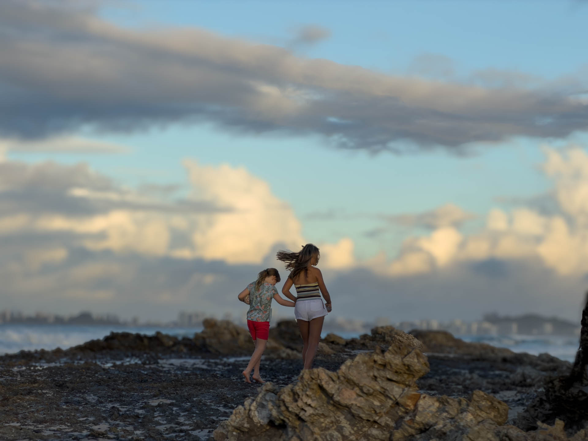 Children on Elephant Rock at Currumbin in golden-hour light, the surf breaking behind them.